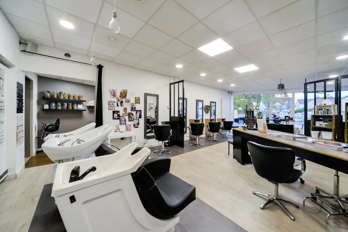 Les bacs à shampoing et les postes du salon, la vitrine en fond