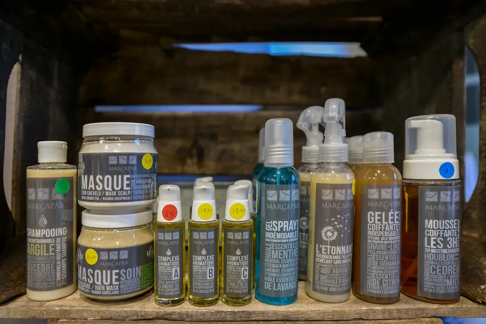 Les soins Marcapar du salon, masques, shampoing à l’argile et sprays, rangés dans une caisse en bois